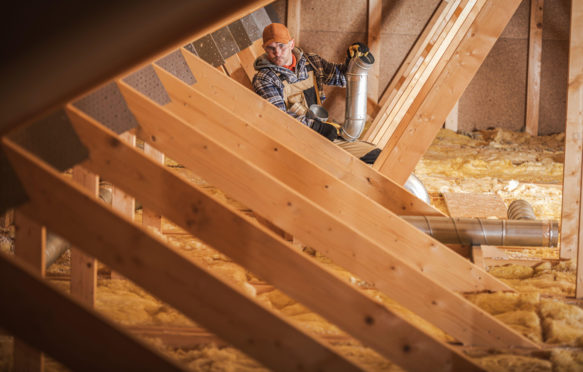 Worker installing heating and air conditioning system in an insullated attic. Credit: Tomasz Zajda / Alamy Stock Photo