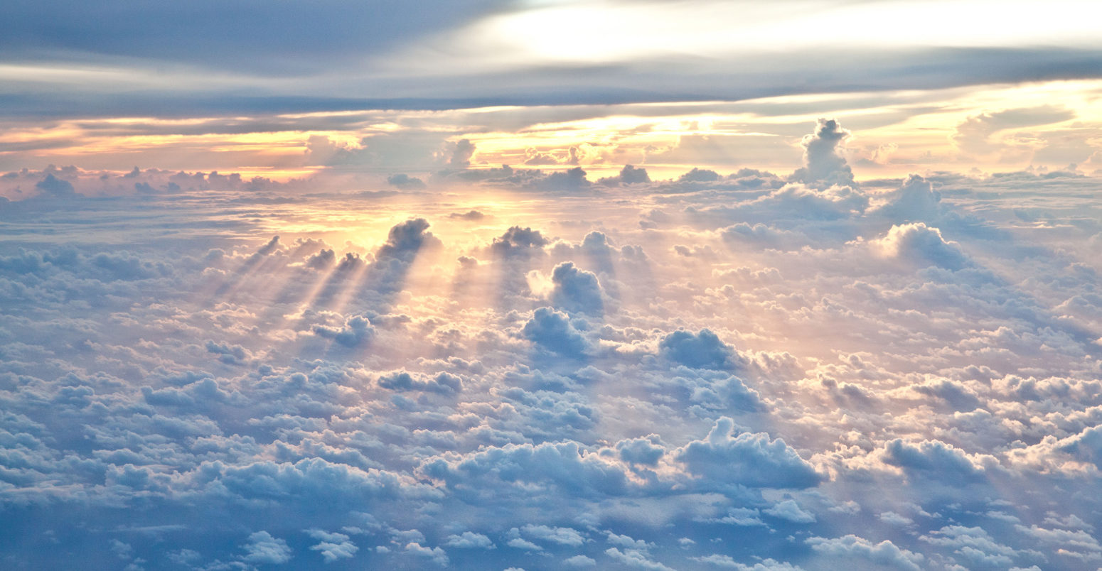 Sun rays shine through the clouds as dusk approaches.