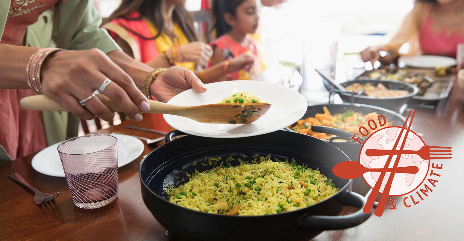 Indian women in saris serving and eating food at table. Credit: Barry Diomede / Alamy Stock Photo.