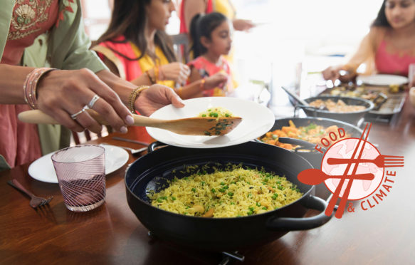 Indian women in saris serving and eating food at table. Credit: Barry Diomede / Alamy Stock Photo.