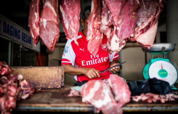 A butcher prepares cuts of meat in Kota Kinabalu, Malaysian Borneo.