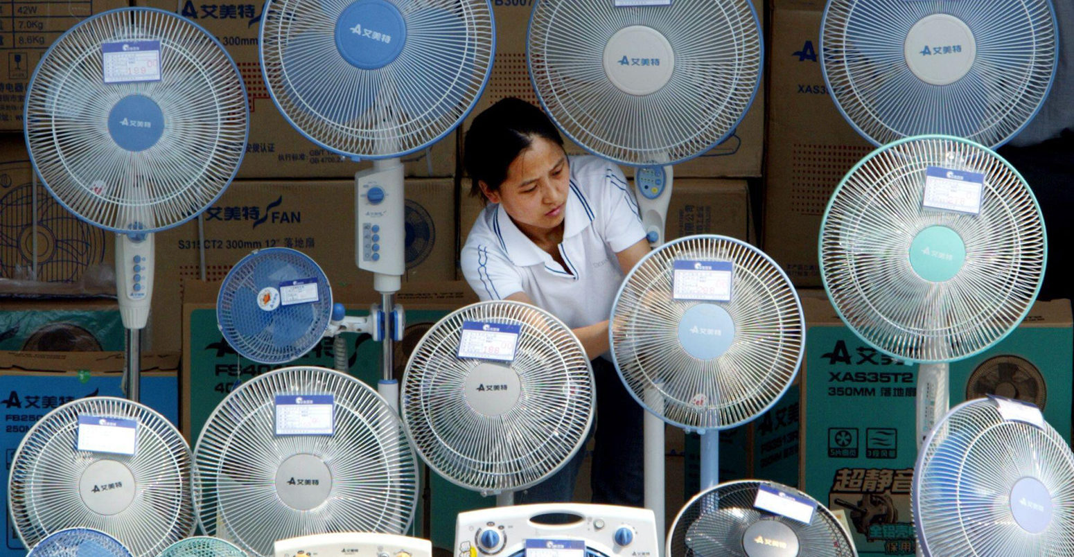 A Chinese woman cleans electric fans at an outdoor stall in Beijing.