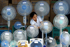 A Chinese woman cleans electric fans at an outdoor stall in Beijing.