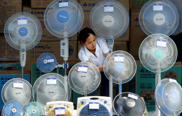 A Chinese woman cleans electric fans at an outdoor stall in Beijing.