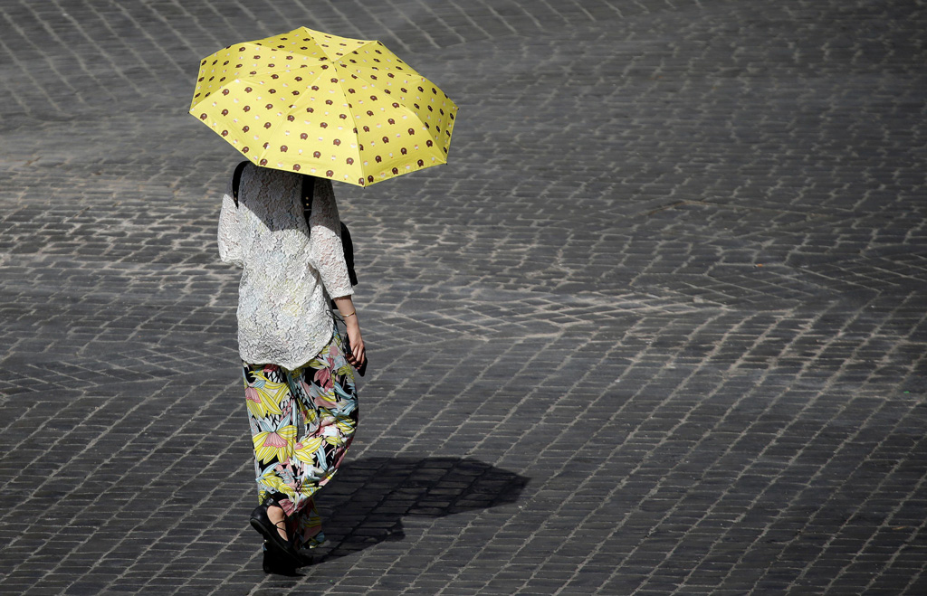 A woman shelters from the sun in downtown Rome as a heatwave hits Italy. 