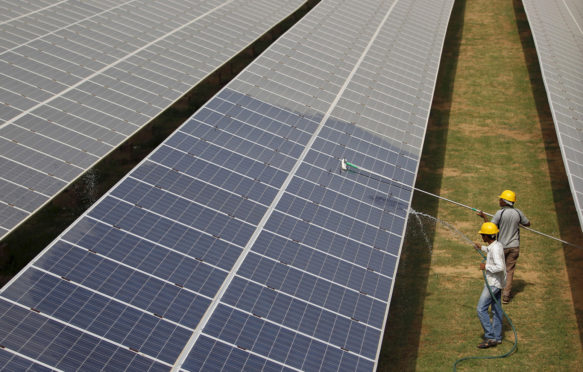 Workers clean photovoltaic panels inside a solar power plant in Gujarat, India.