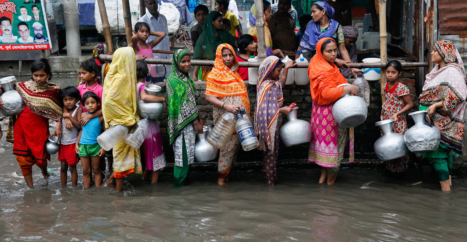 Women and children collect drinking water from a water logged area in Dhaka, Bangladesh, June 2017. Credit: Mehedi Hasan/Alamy Stock Photo.