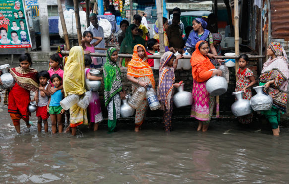 Women and children collect drinking water from a water logged area in Dhaka, Bangladesh, June 2017. Credit: Mehedi Hasan/Alamy Stock Photo.