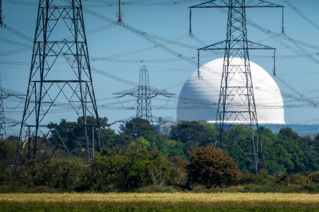 Sizewell B nuclear power plant with several electricity pylons in front seen through a distorting heat haze.