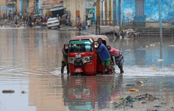 Somali-men-push-their-rickshaw-through-flood-waters-after-a-flash-flood-in-Mogadishu,-Somalia