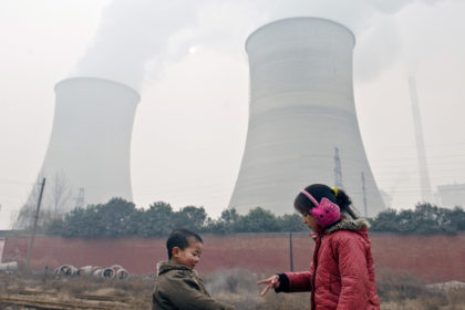 Two-young-kids-play-the-finger-guessing-game-near-cooling-towers-and-chimneys-discharing-smoke-at-a-coal-fired-power-plant-in-heavy-smog-in-Luoyang-city-China