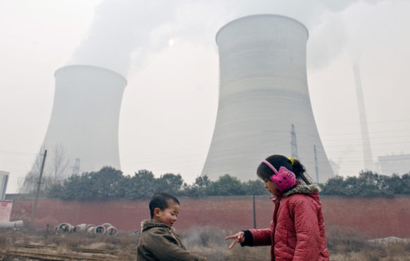 Two-young-kids-play-the-finger-guessing-game-near-cooling-towers-and-chimneys-discharing-smoke-at-a-coal-fired-power-plant-in-heavy-smog-in-Luoyang-city-China