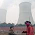 Two-young-kids-play-the-finger-guessing-game-near-cooling-towers-and-chimneys-discharing-smoke-at-a-coal-fired-power-plant-in-heavy-smog-in-Luoyang-city-China