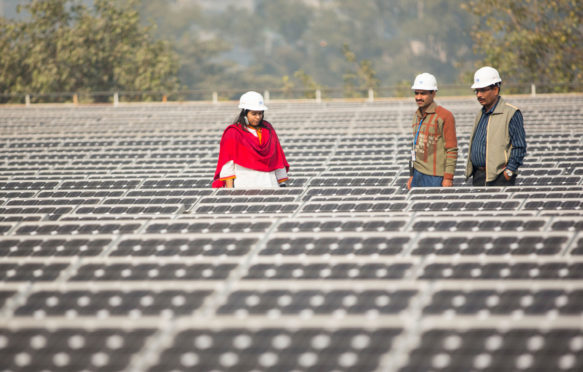 Workers-at-a-1MW-solar-power-station-run-by-Tata-Power-on-the-roof-of-an-electricity-company-in-Delhi,-India
