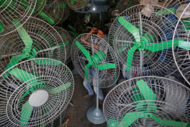 A mechanic uses a hammer to fix steel guard of an electric fan inside a shop in Mumbai