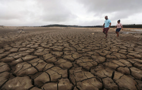 A-family-negotiates-their-way-through-caked-mud-at-Theewaterskloof-dam-at-as-Cape-Town-faces-Day-Zero