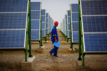 A worker inspects solar panels at a solar farm in Dunhuang