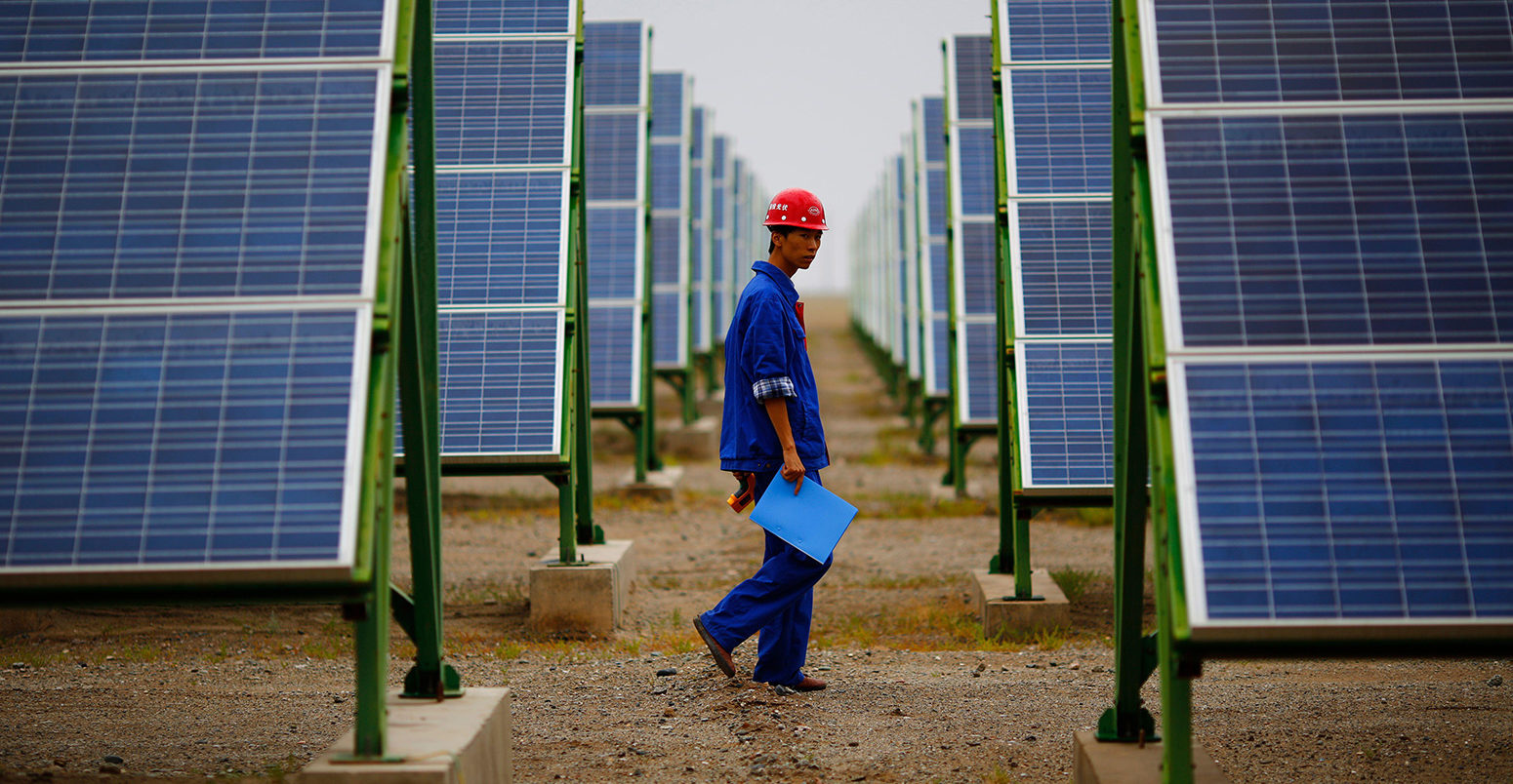 A worker inspects solar panels at a solar farm in Dunhuang