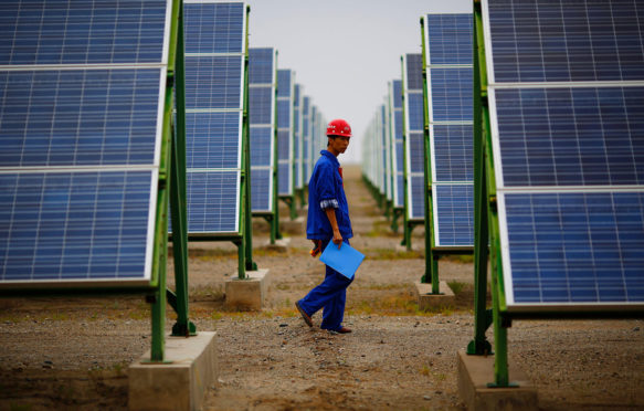 A worker inspects solar panels at a solar farm in Dunhuang