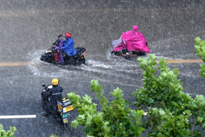 People ride on a waterlogged road in Zhengzhou after torrential rains