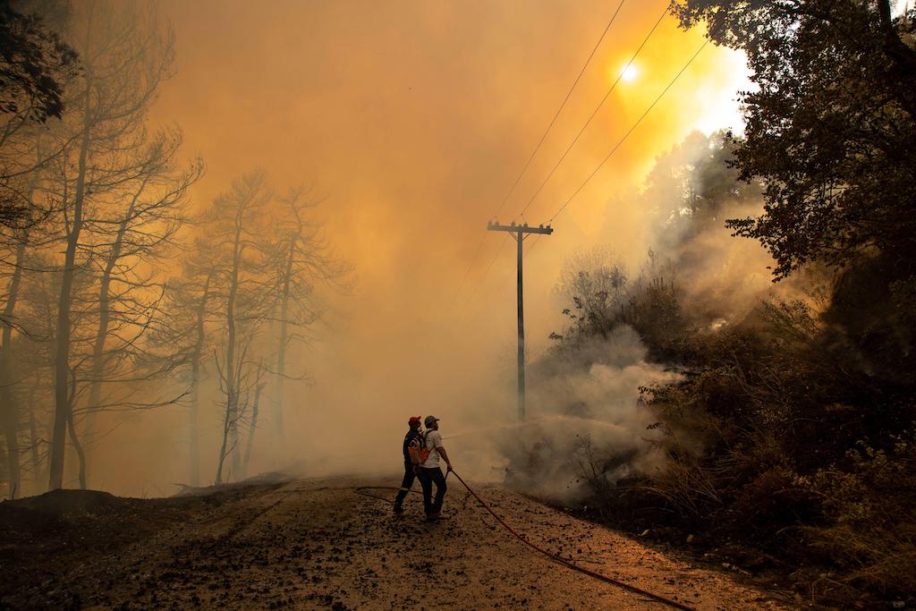 Firefighter and local volunteers extinguishing a fire on Evia Island in Greece_2GEWT8P