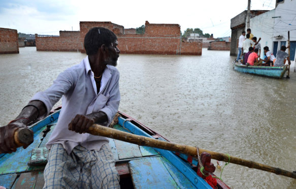 A man paddles a boat in the flooded village of Varanasi, India