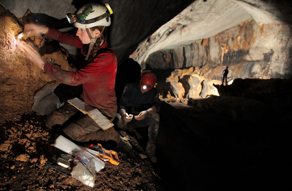 Female PhD student takes core sediment samples from a mud bank in a cave in Mulu National Park, Borneo