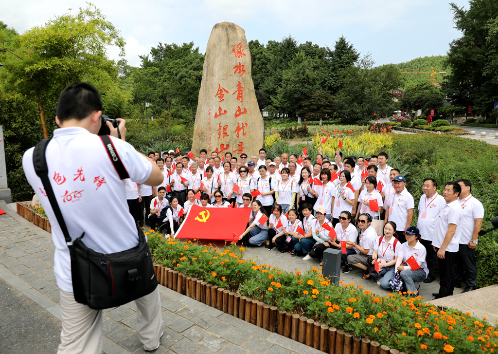 Group photo in front of the stone monument marking Xis 2005 Lucid waters and lush mountains speech