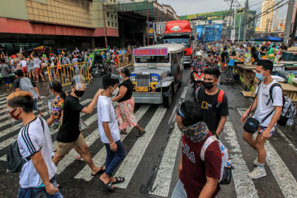 People wearing protective masks are seen at a busy street in Manila, March 2021
