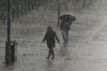 Two people hurry along the Southbank in London as torrential downpour continues