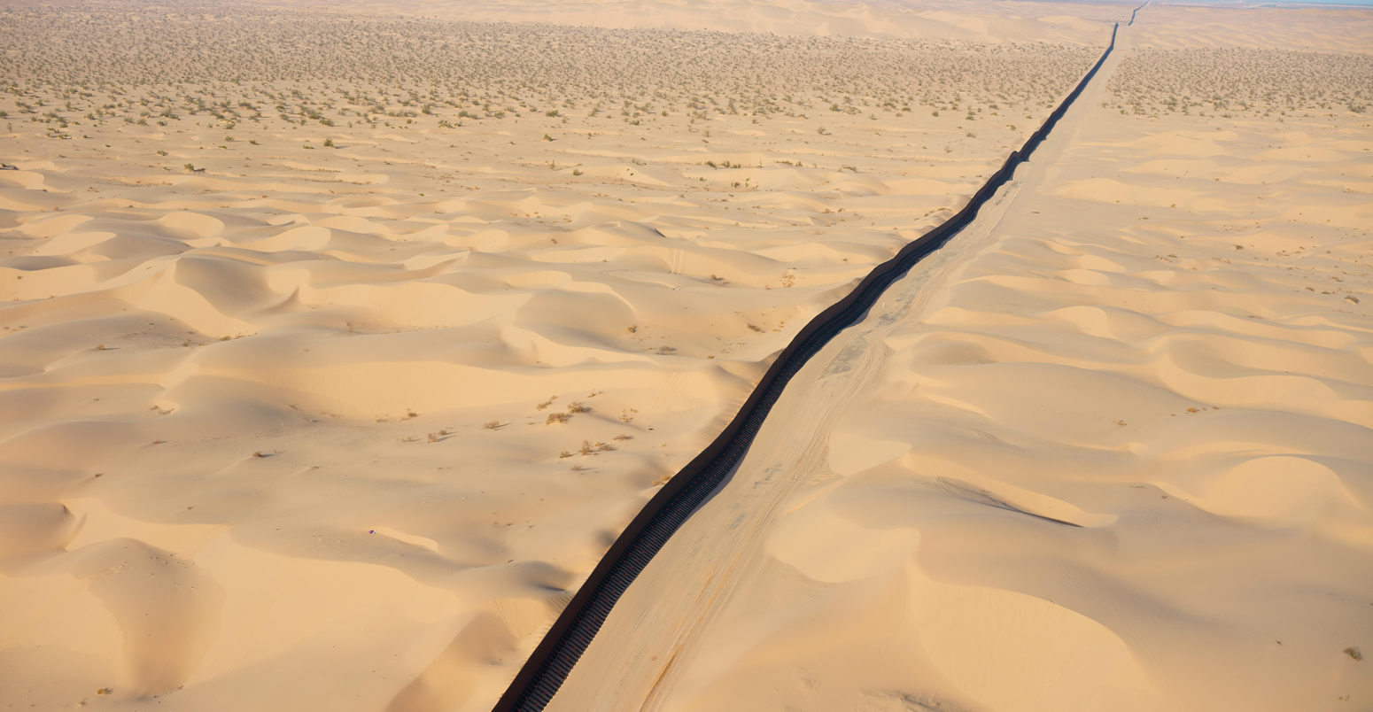 INTERNATIONAL BORDER: MEXICO - UNITED STATES (aerial view). Algodones Dunes in the Sonoran Desert, Baja California, Mexico (left of wall)