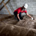 A worker lays loft insulation in the attic of a residential property in Cornwall, UK