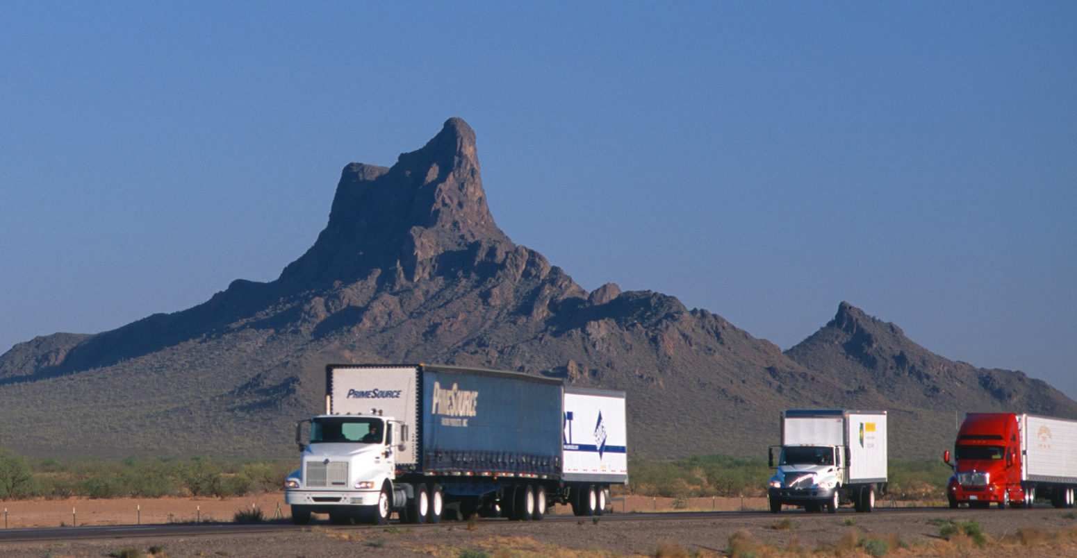 Trucks on desert highway in Arizona, US. Credit: Chris Alan Selby / Alamy Stock Photo. BKNB4K