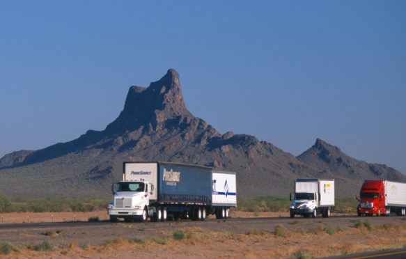 Trucks on desert highway in Arizona, US. Credit: Chris Alan Selby / Alamy Stock Photo. BKNB4K