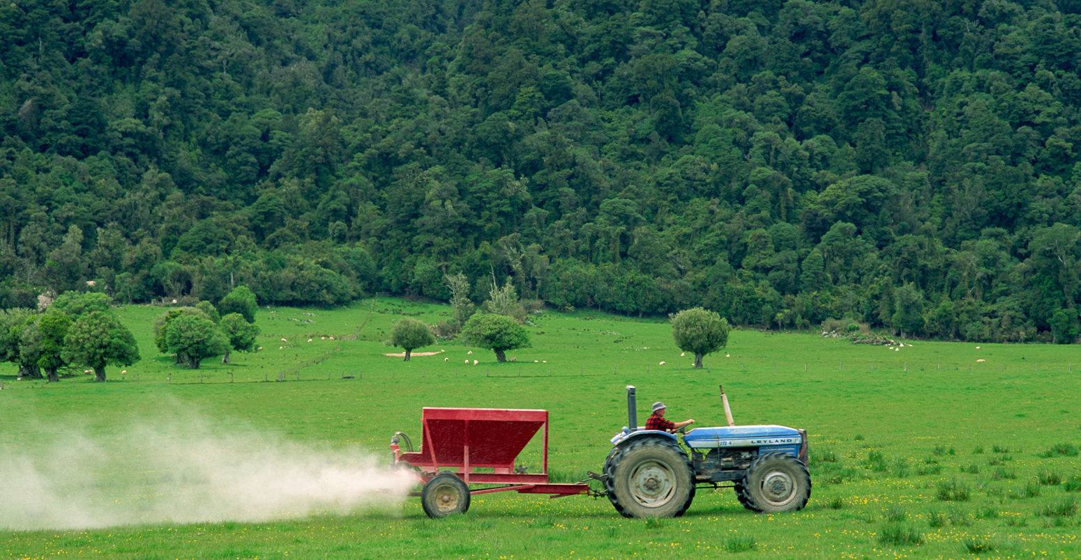 Farmer spraying fertiliser on a field for sheep grazing in New Zealand