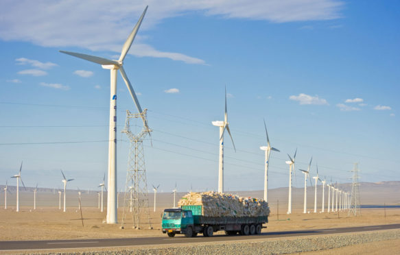 A truck travelling along the G30 Lianhuo expressway with part of the Daheyan wind farm in the background in Xinjiang, China. Credit: Paul Springett D / Alamy Stock Photo