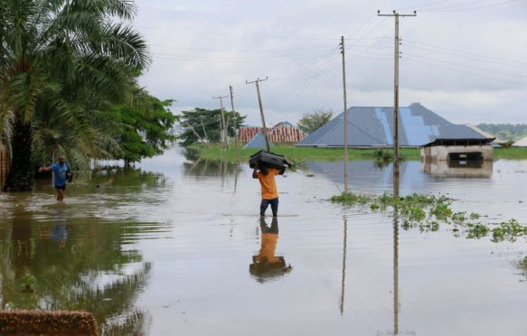 A man wades through flood water in Nigeria.