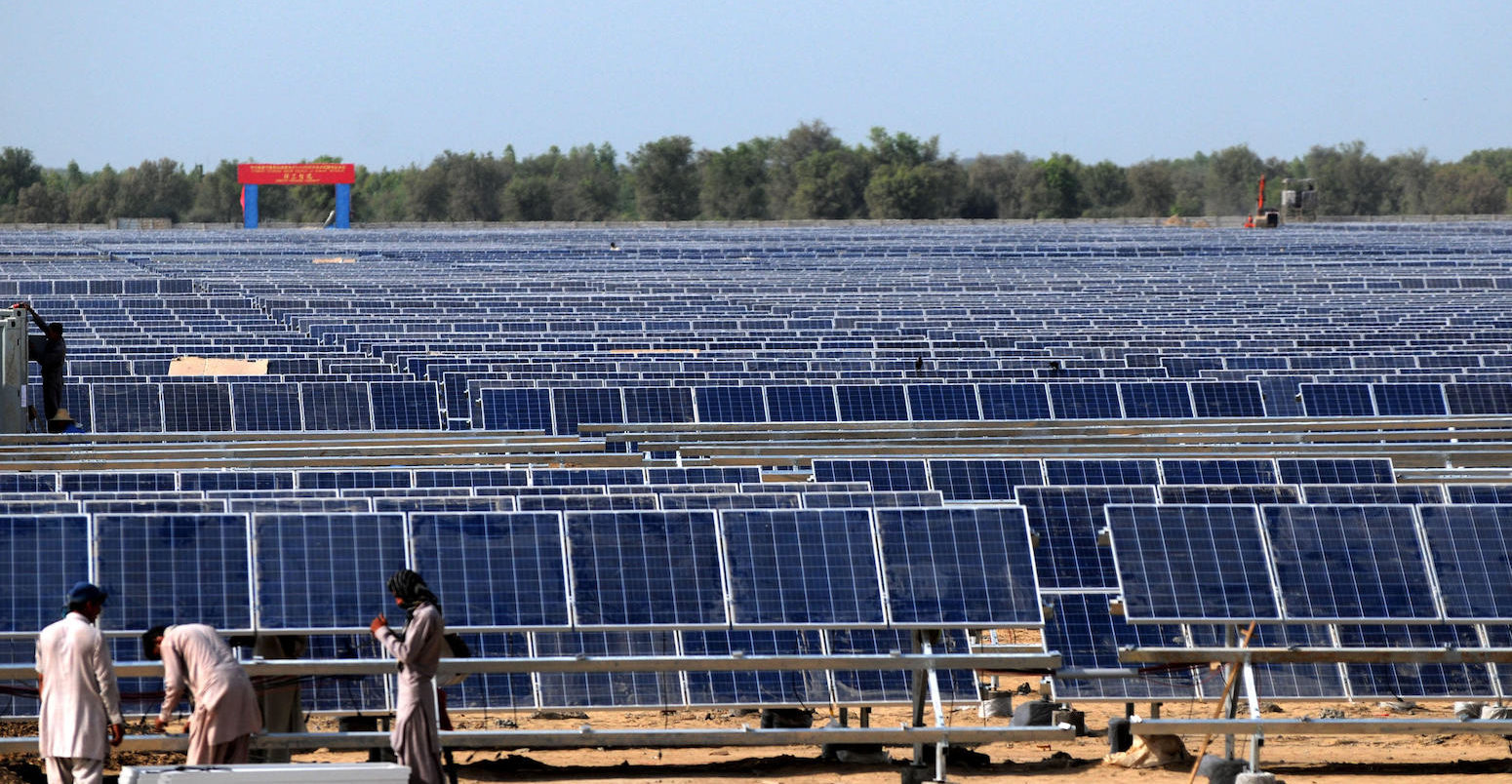 Workers install solar photovoltaic panels in Pakistan.