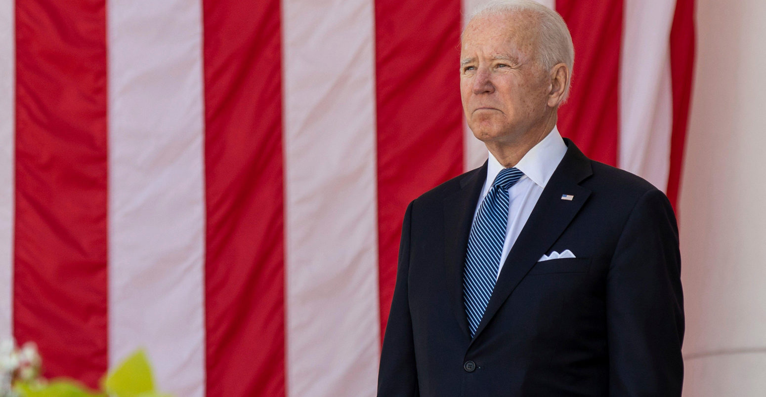 US President Joe Biden stands in front of the United States national flag