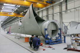 Workers next to a giant wind turbine blade at the factory VentoMoinho at Viana do Castelo, Portugal.