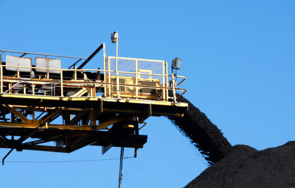 Yellow coal Conveyor belt carrying coal and pouring onto a pile in Australia.