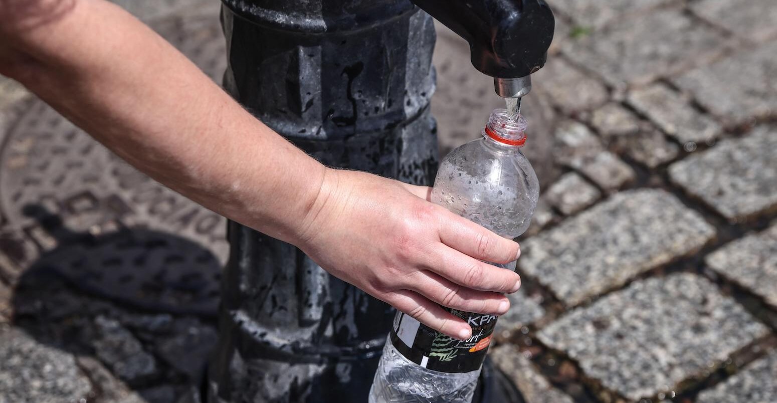 A person pours tap water into a plastic bottle at the Main Square in Krakow, Poland, on 19 June 2022.