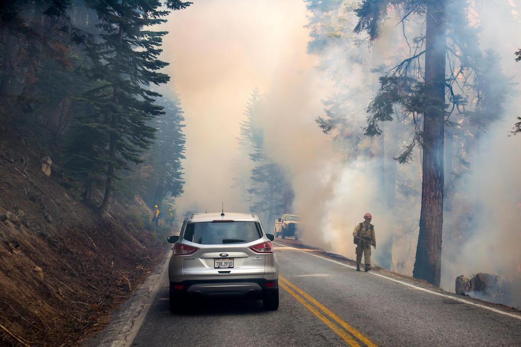 A car driving through a forest fire in Yosemite National Park, US, 2017. Image ID: KFHFRN.