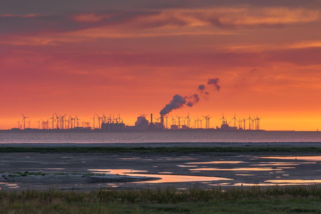 The Wadden Sea, factory buildings and wind turbines at sunset, Eemshaven, Netherlands.