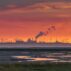 The Wadden Sea, factory buildings and wind turbines at sunset, Eemshaven, Netherlands.