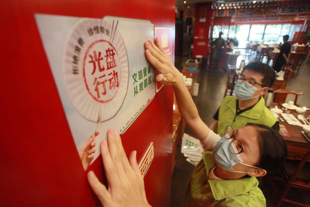 Staff at a local restaurant put up signs with characters saying "Clean Plate Campaign" to urge people against food waste, Yangzhou city, east China's Jiangsu province, 21 August 2020. Image ID: 2EKE6DK.