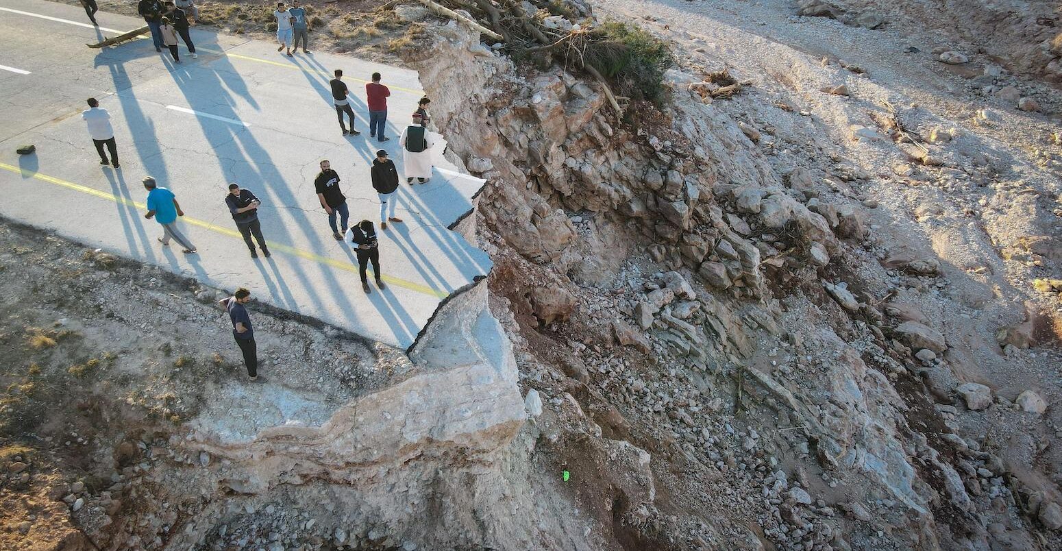 People in east Libya standing on a broken highway destroyed in recent heavy floods.