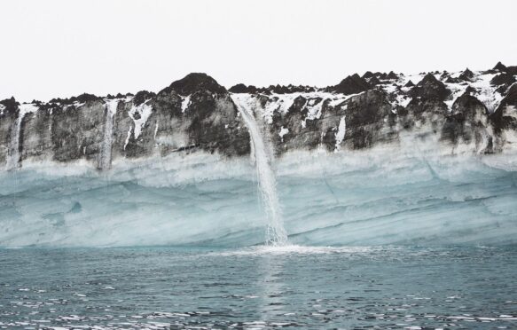 Snowmelt waterfall pouring over cliffs into ocean, Antarctic Peninsula, Weddell Sea, Antarctica.