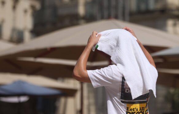 A person covers themselves with a towel as temperatures reach 38C in Montpellier, France on 19 July 2023.
