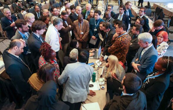 IPCC delegates negotiating in a huddle in Istanbul, Türkiye.